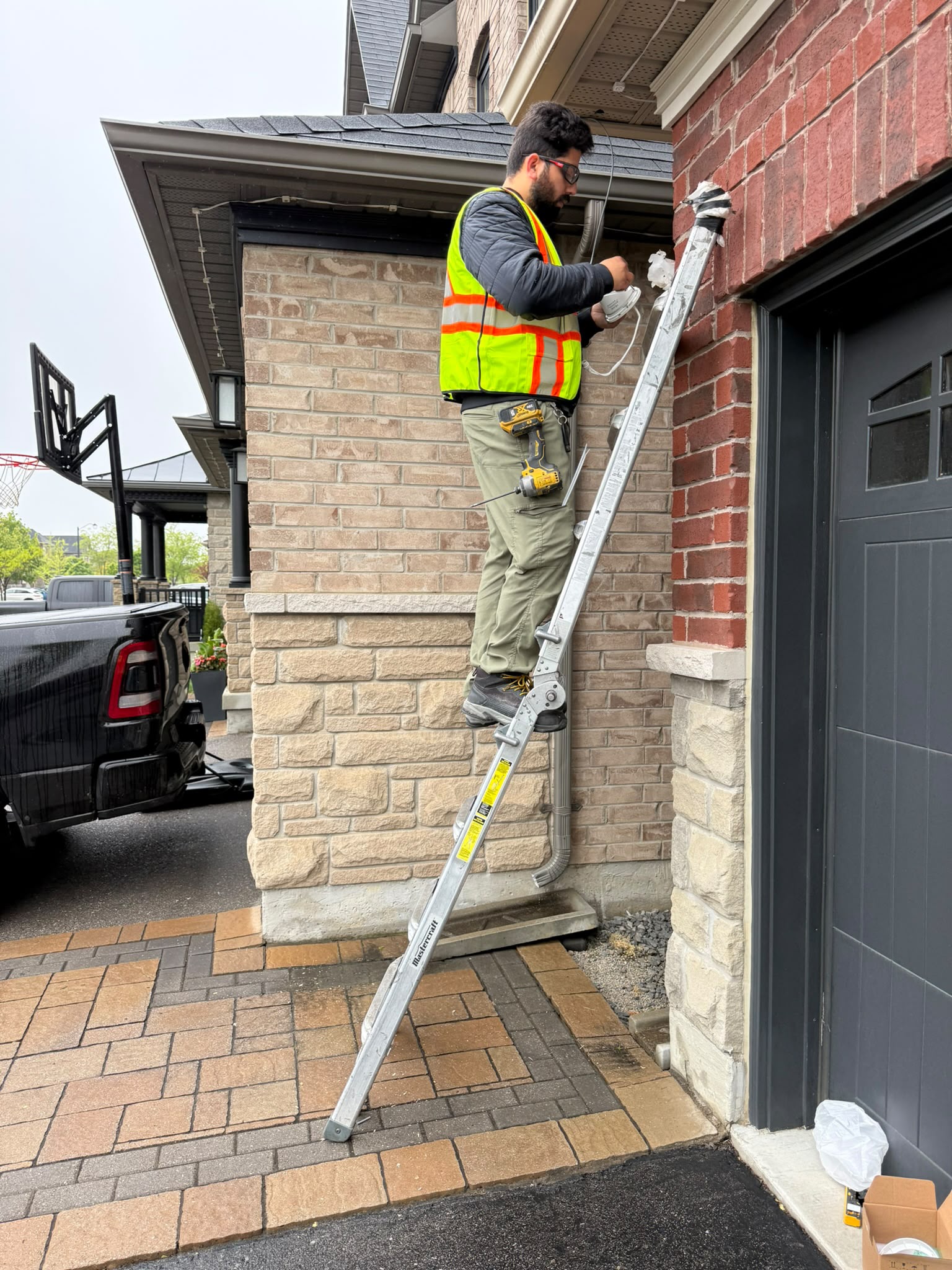 Technician on ladder installing outdoor security camera
